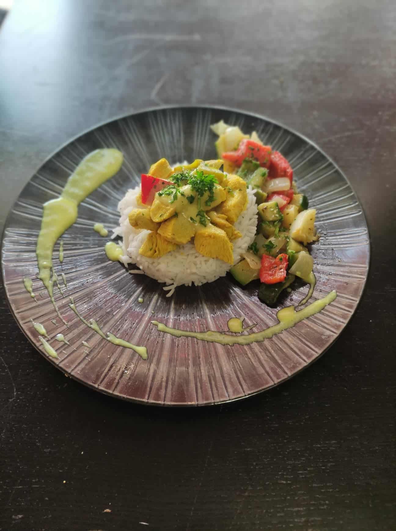 Une succulent assiette composée de poulet au citron accompagné de petits légumes et de riz.