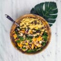 Salade exotique avec des haricots rouges, du quinoa, de la tomate présentée dans un bol en bambou posé sur une feuille de palmier.