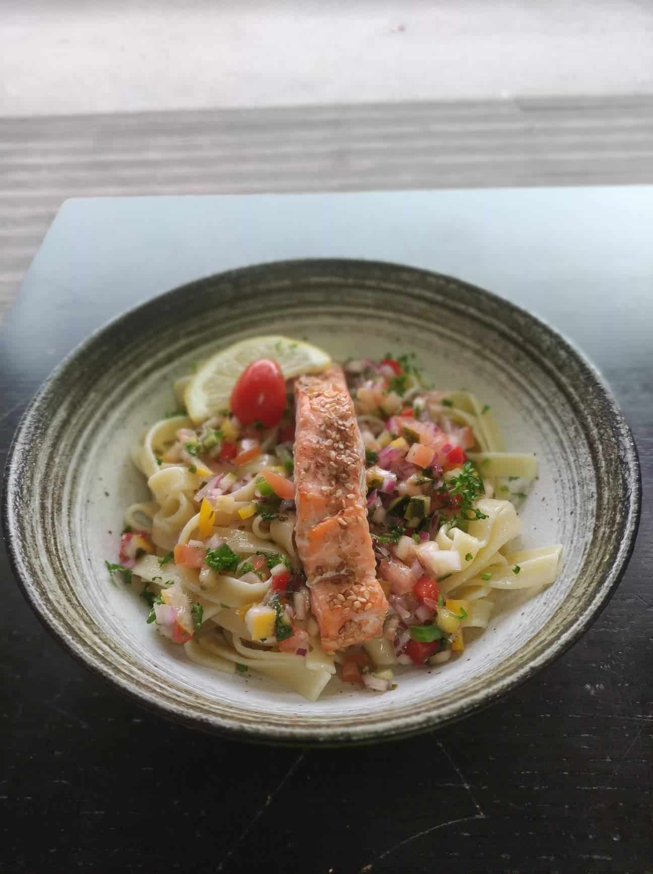 Un assiette de tagliatelles et petits légumes, avec un joli pavé de saumon.
