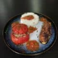 Une belle assiette composée d'une tomate et d'une courgette farcie.