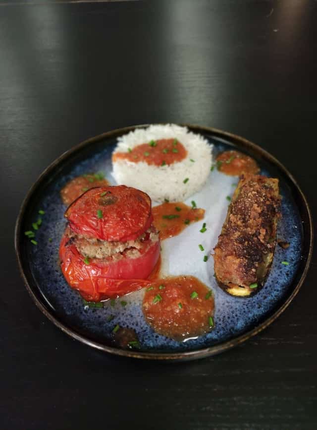 Une belle assiette composée d'une tomate et d'une courgette farcie.