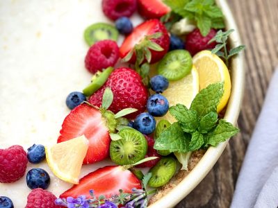 Composition de fruits sur une crème brûlée dans un bol : myrtilles, fraises, framboises, citron, kiwi et feuilles de menthe.