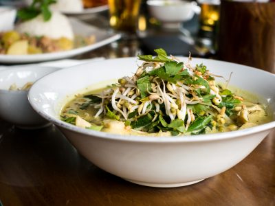 Salade de pousses de soja, basilic et persil dans un saladier blanc disposé sur une table.
